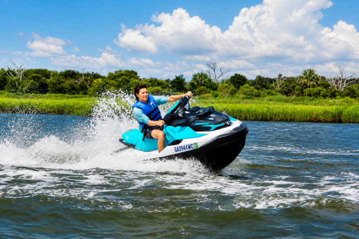 Person in blue life vest riding a jet ski on a river.