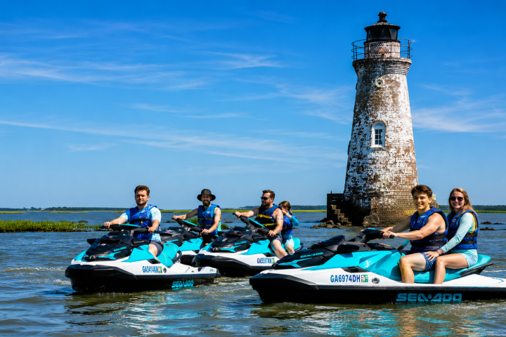 People on jet skis near an old lighthouse on a sunny day.